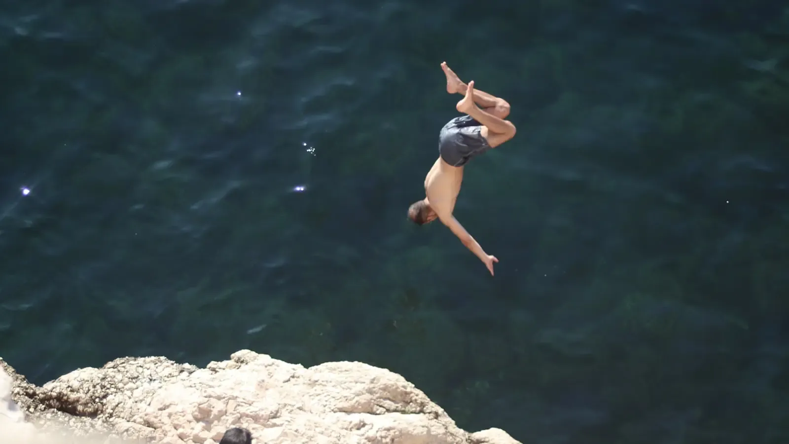 How do professional cliff divers survive the impact of a 50 mph descent
